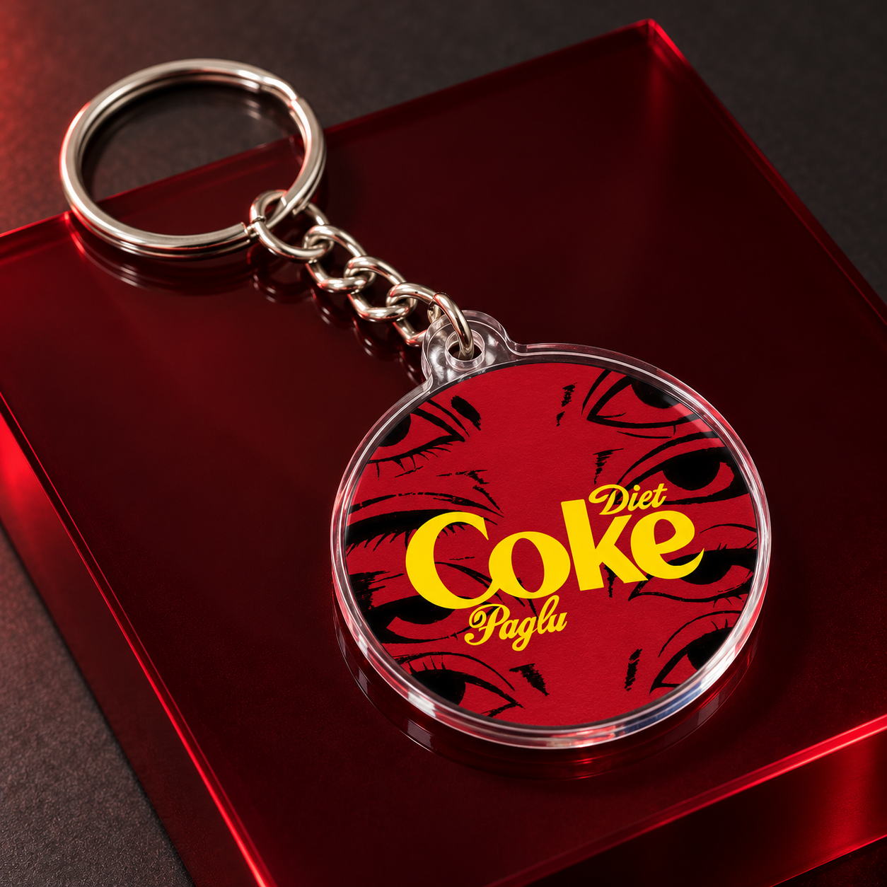 Diet Coke Paglu illustrated acrylic keychain on a red studio display